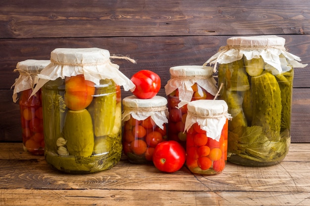 Homemade canned vegetables in cans. Pickled tomatoes and cucumbers in a rural style.