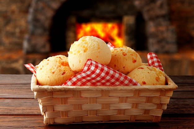 Homemade cheese bread, traditional Brazilian snack, in the basket after leaving the oven on a rustic kitchen table