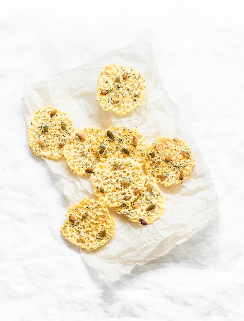 Homemade cheese chips with pumpkin seeds on a light background top view