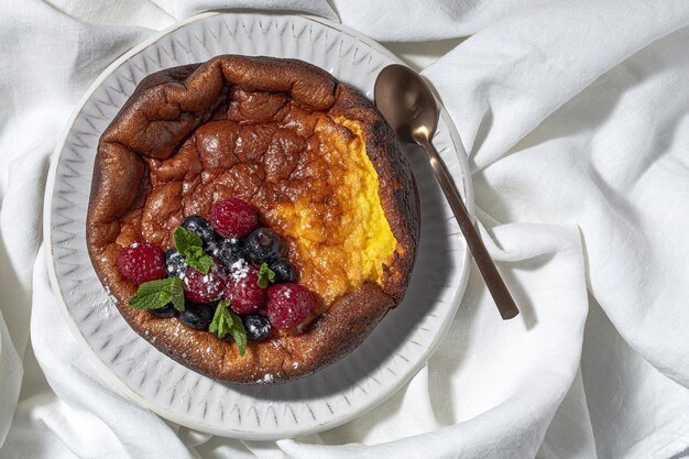 Cheesecake fatta in casa con mirtilli, ribes, fragole e foglie di menta dall'alto. lay piatto