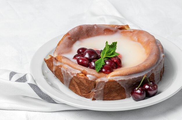 Homemade cheesecake with cherries and mint on white wall