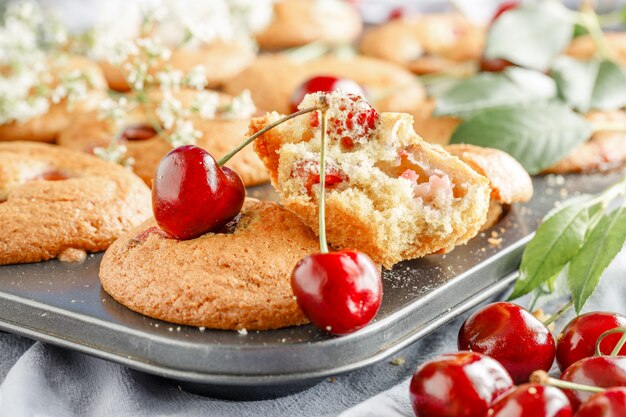 Homemade cherry muffins and fresh cherries on a light background