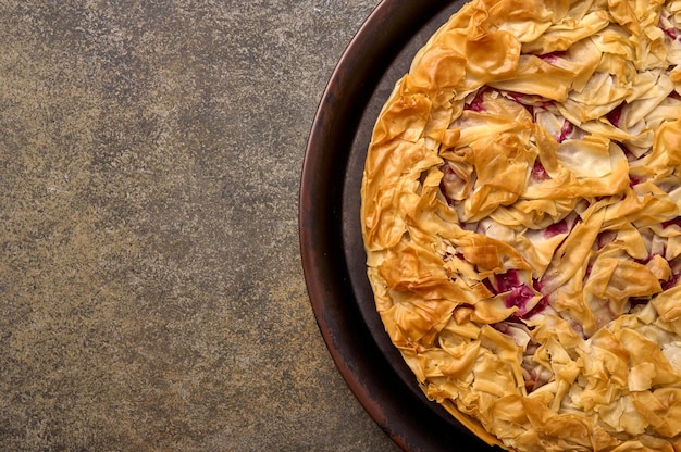 Homemade cherry pie from filo dough on wooden background top view copy space close up