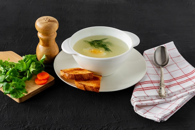 自家製チキンブイヨンまたはスープ。健康的な朝食。黒のコンクリートの背景