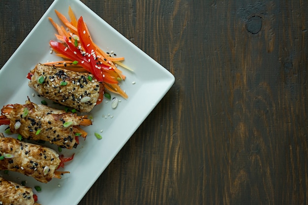 Petto di pollo fatto in casa con verdure, fette di carota, peperone su un piatto rettangolare leggero.