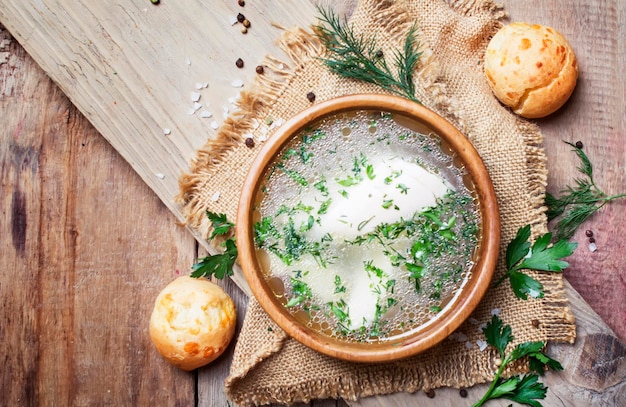 Brodo di pollo fatto in casa con carne bianca ed erbe aromatiche in stile rustico vintage sfondo in legno vista dall'alto