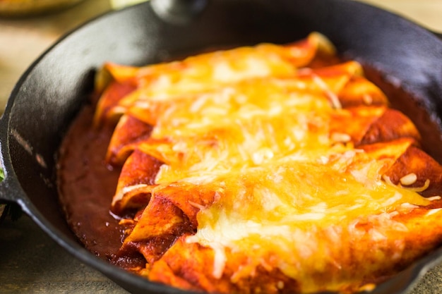 Homemade chicken enchiladas in cast iron frying pan.