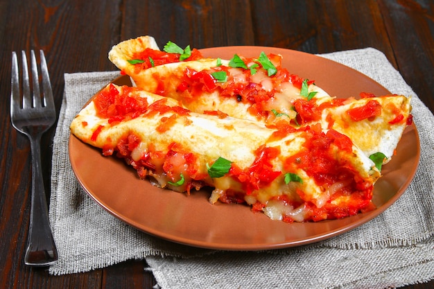 나무 테이블에 접시에 만든 치킨 enchiladas입니다. 평면도.