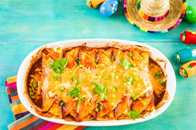 Homemade chicken enchiladas garnished with green onions and cilantro in a white casserole dish.