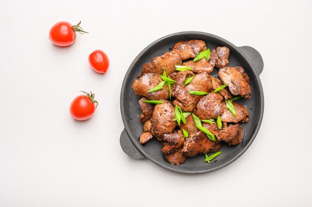 Homemade chicken liver fried with soy sauce, tomatoes, onions and spices on light background.