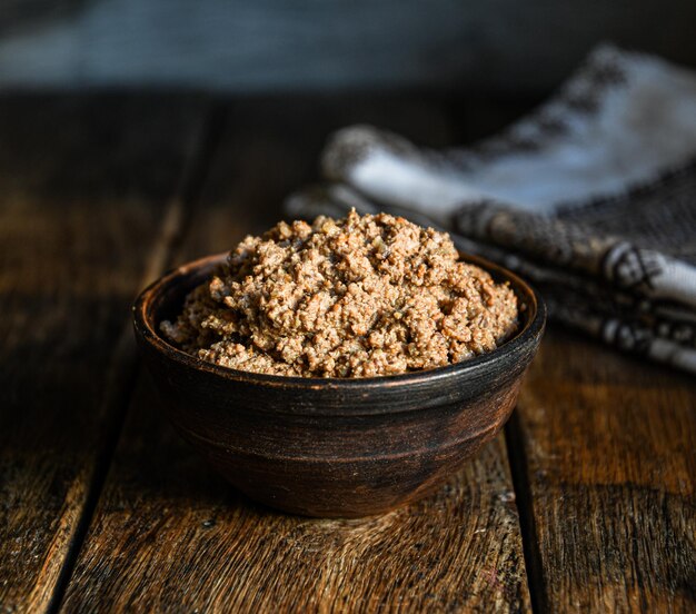 Homemade chicken liver pate in a ceramic dish on a wooden background.