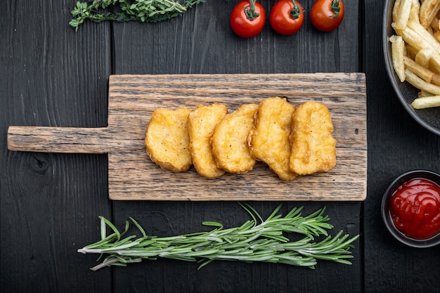 Pepite di pollo fatte in casa fritte sulla tavola di legno nera, vista dall'alto