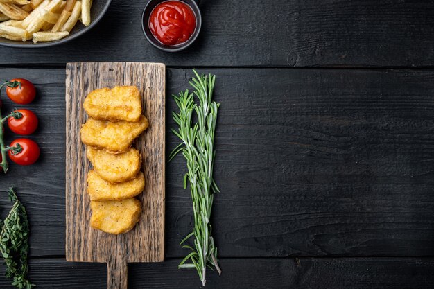 Homemade chicken nuggets fried on black wooden table, top view,.