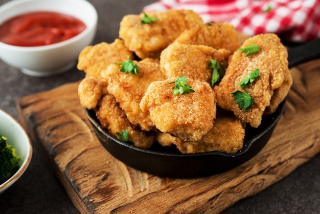 Homemade chicken nuggets with vegetables on a wooden board