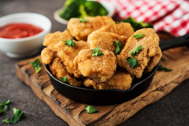 Homemade chicken nuggets with vegetables on a wooden board