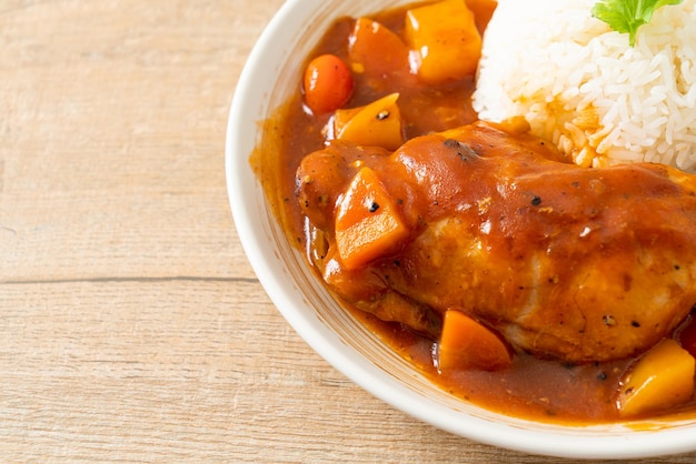 homemade chicken stew with tomatoes, onions, carrot and potatoes on plate with rice