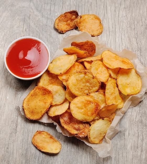 Homemade chips with tomato sauce on wooden tables . Potato chips