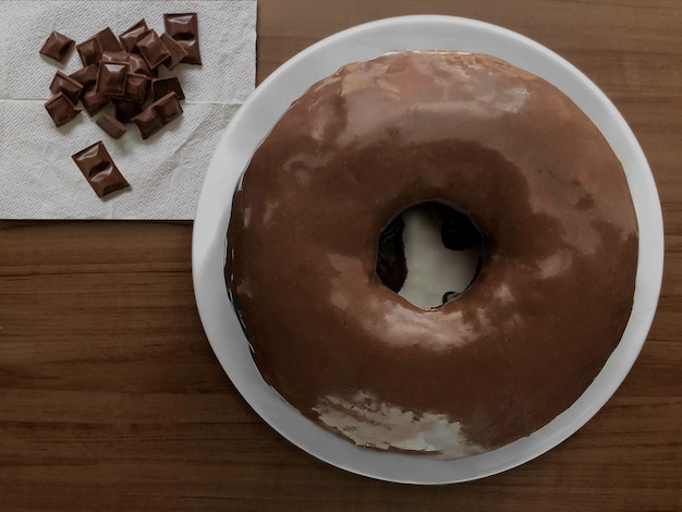 Homemade chocolat cake on a wooden board with pieces of chocolate on the side