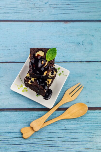 Brownie al cioccolato fatti in casa su uno sfondo di legno blu con posate in legno