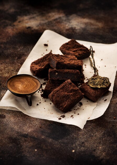 Homemade chocolate brownies and a cup coffee on a brown concrete background