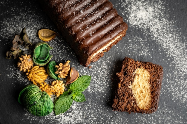 Homemade chocolate cake on black slate with dried leaves