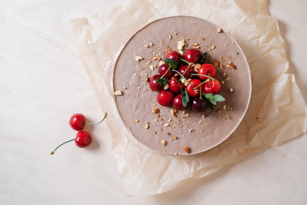 Homemade chocolate cake with cherry on parchment paper food\
delivery homemade baking top view delicious tart with chocolate and\
cherry on the wooden table