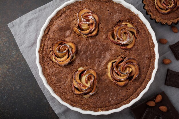 Homemade chocolate cake with frangipane and apple blossoms on a dark concrete