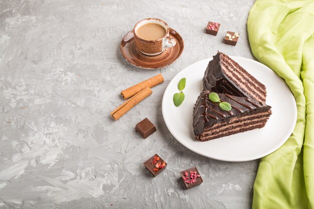 Homemade chocolate cake with milk cream and a cup of coffee on a gray concrete surface. side view, copy space.