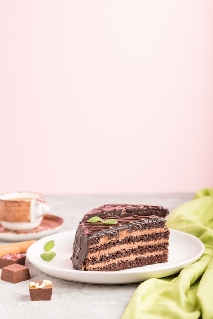 Homemade chocolate cake with milk cream and a cup of coffee on a gray surface. side view, selective focus, copy space.