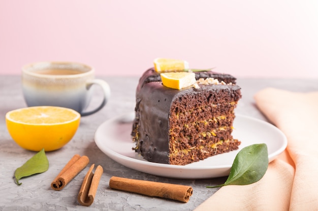 Homemade chocolate cake with orange and cinnamon with cup of coffee on a gray and pink background. side view, selective focus.