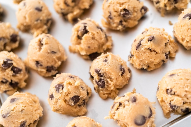 Homemade chocolate chip cookies dough scoops on a baking sheet.