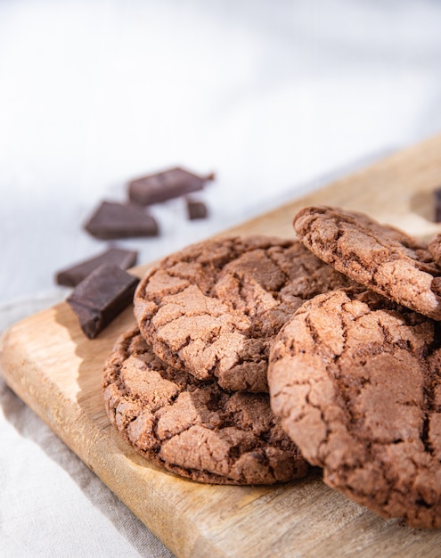 Homemade chocolate cookies with chocolate chips on wood cutting board  on a light table. Macro view and close up