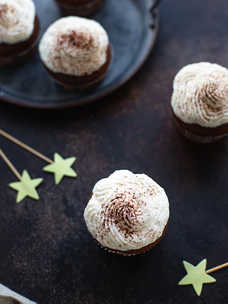 Homemade chocolate cupcakes or muffins with cream. dark background. vertical image.