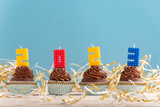 Homemade chocolate cupcakes with 2023 number colorful candle on blue background Happy New Year theme