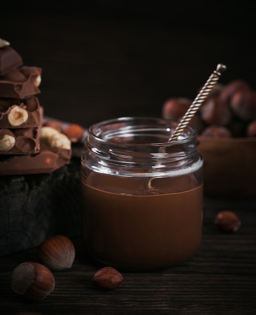 Homemade Chocolate Hazelnut Milk Spread on glass jar on dark wooden surface