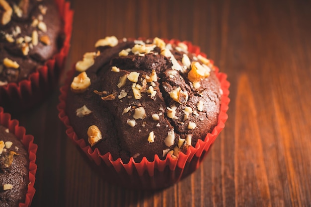 Homemade chocolate muffins or cupcakes sprinkled of nuts on a wooden board