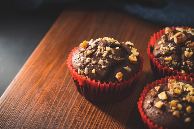 Homemade chocolate muffins or cupcakes sprinkled of nuts on a wooden board