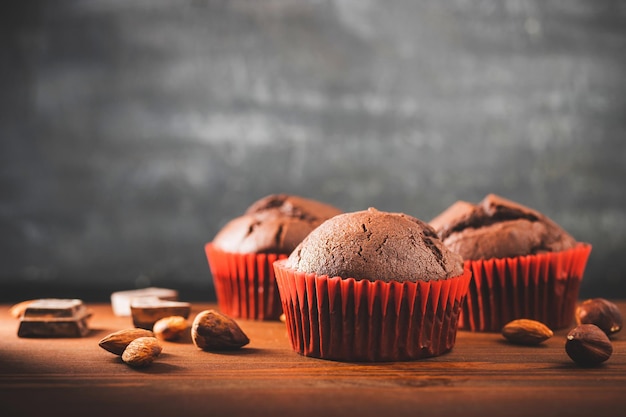 Homemade chocolate muffins or cupcakes on a wooden table and dark background