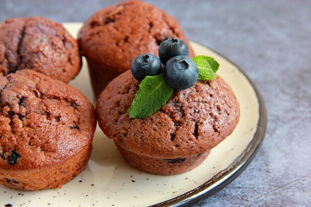 Homemade chocolate muffins with blueberries and fresh mint on the plate
