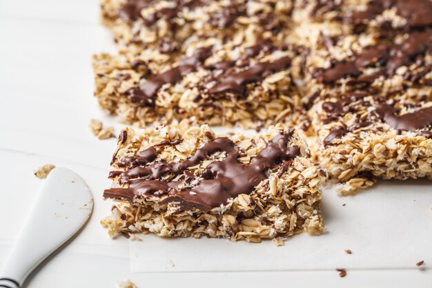 Barrette di avena al cioccolato artigianale su sfondo bianco. dessert vegano sano, cibo detox, a base vegetale.