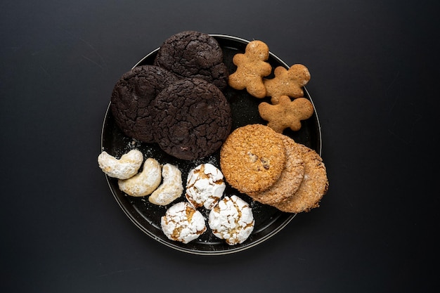 사진 검은 접시에 검은 배경에 설탕을 뿌린 수제 초콜릿 오트밀 쿠키
