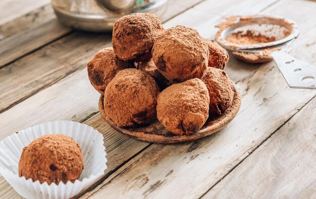 Homemade chocolate truffles candy ball on a plate sprinkled with cocoa on a rustc wooden background top vew