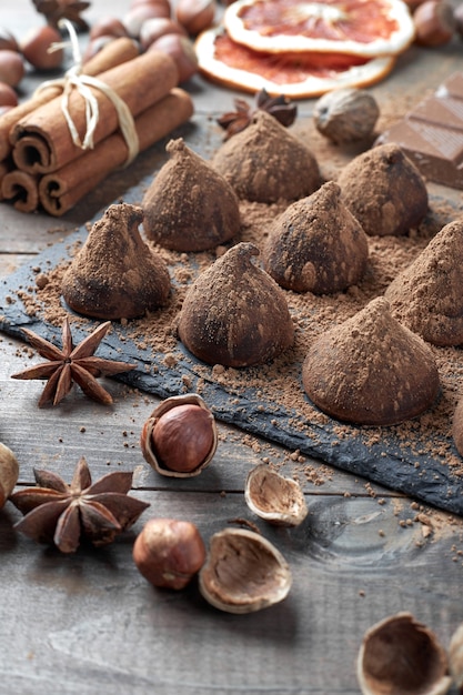Photo homemade chocolate truffles sprinkled with cocoa powder and assorted chocolate with nuts and other spices on rustic old kitchen table.
