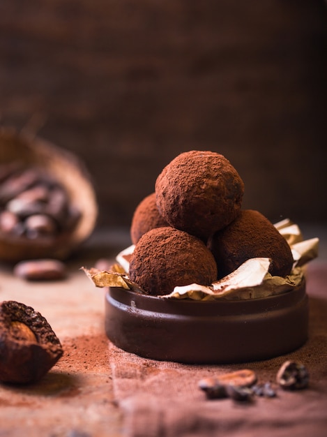 Homemade chocolate truffles  on wooden table closeup view. Tasty vegetarian candy or balls  with raw cocoa powder