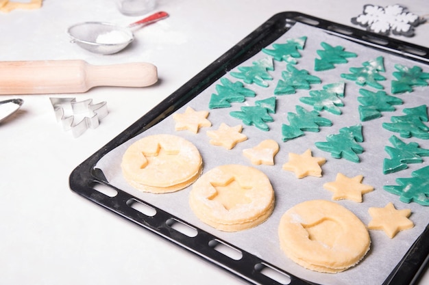Homemade Christmas cookies before baking on a baking sheet on a table with a white tablecloth
