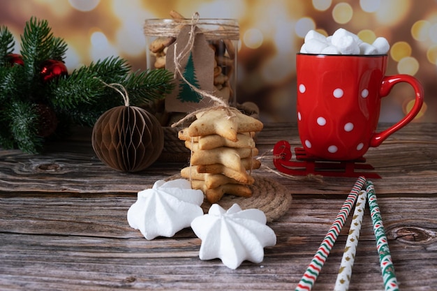 Homemade Christmas cookies stacked on top of each other with a cup of hot cocoa with marshmallow