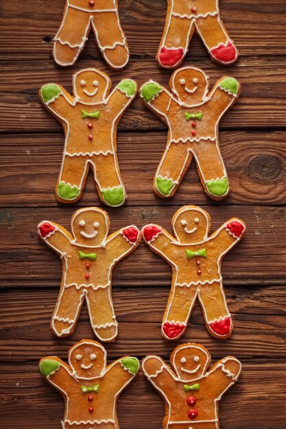 Homemade christmas gingerbread men with icing pattern on brown wooden surface