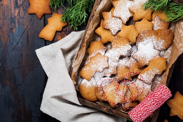 Homemade Christmas star shape gingerbread cookies in wooden box on old wooden surface. Top view