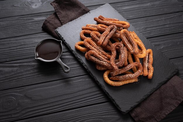 Homemade churros with chocolate on a dark wooden rustic background