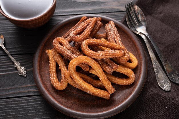 Homemade churros with chocolate on a dark wooden rustic background